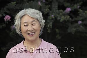 Asia Images Group - Portrait of older woman smiling in front of flowers