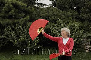 Asia Images Group - Older woman dancing with fan dance outdoors
