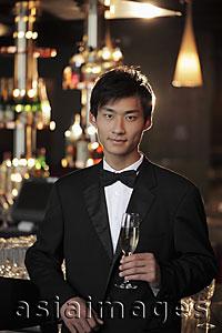 Asia Images Group - Young man dressed in a tuxedo holding a champagne glass at night