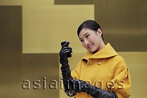 Asia Images Group - Young woman wearing black gloves looking at phone