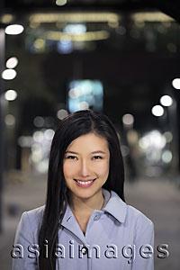 Asia Images Group - Head shot of young woman standing on the street at night