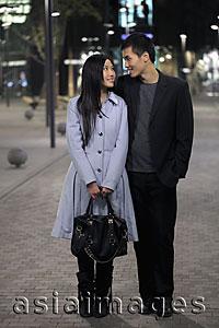 Asia Images Group - Young couple standing on the street at night looking at each other