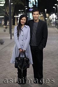 Asia Images Group - Young couple standing on street at night.