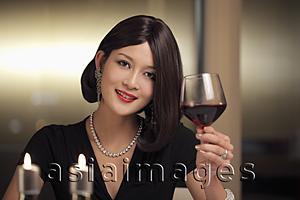 Asia Images Group - Young woman drinking wine during a candle lit dinner