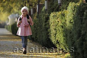 Asia Images Group - Young girl walking down street wearing pink coat and hat and backpack