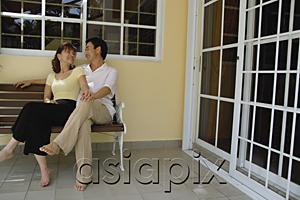 AsiaPix - Couple sitting on bench in patio, looking at each other