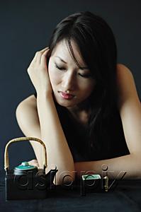 AsiaPix - Woman with eyes closed, teacup and teapot next to her
