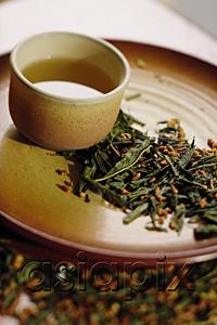 AsiaPix - Tea cup on tray, tea leaves scattered around