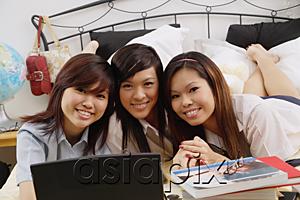 AsiaPix - Girls in school uniform lying side by side on bed, smiling at camera