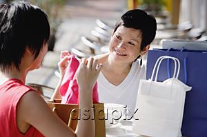 AsiaPix - Two women at cafe, looking at items from their shopping bags