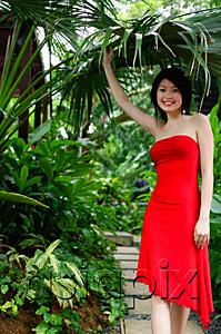 AsiaPix - Woman wearing red dress, standing in garden