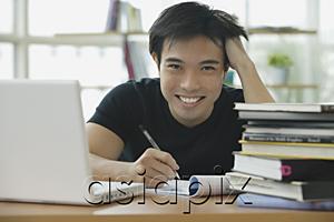 AsiaPix - Young adult  with laptop and books, smiling at camera