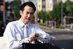 AsiaPix - Businessman looking at watch, frowning