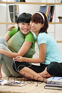 AsiaPix - Young women listening to MP3 player, smiling at camera