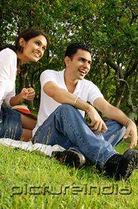 PictureIndia - Couple sitting on grass, looking away