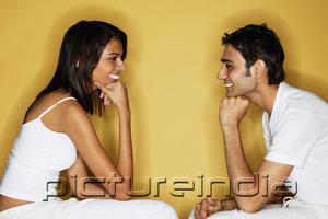 PictureIndia - Couple sitting face to face, hands on chin