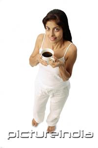 PictureIndia - Woman holding cup of coffee, looking up at camera