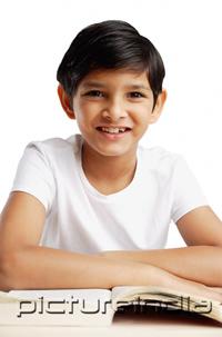 PictureIndia - Boy leaning on book, smiling at camera